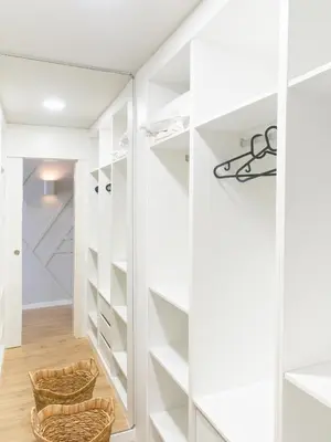 a walk in closet with white cabinets and a mirror at Madeira apartment in Mindelo São Vicente in Mindelo