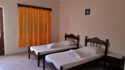 two beds in a room with an orange curtain at Residencial Rosa Criola in Sal Rei