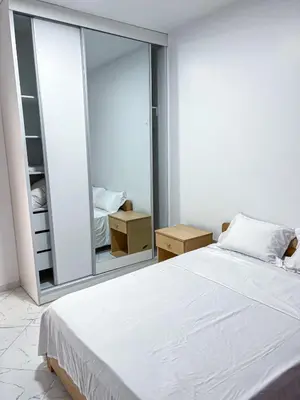 a bedroom with a white bed and a large mirror at Figo Apartamentos in Praia