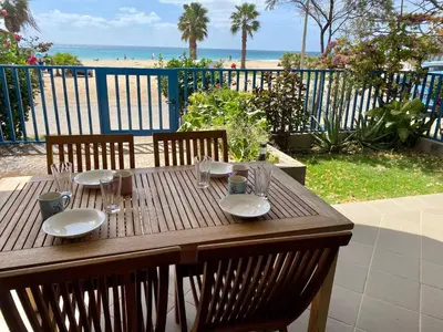 a wooden table with plates and glasses and a view of the beach at Leme Bedje Sea View - By Bobbywashere in Santa Maria