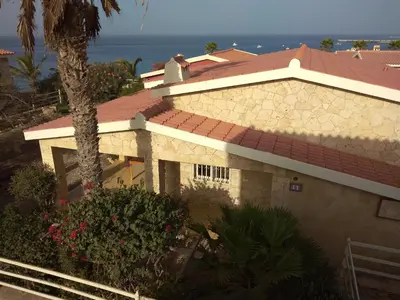 a house with a red roof and a palm tree at Casita Solemar direkt am Atlantik in Vila do Maio