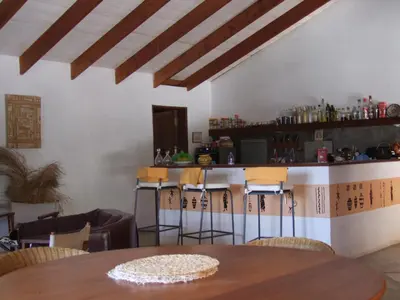 a restaurant with a table and bar with stools at Villa Morabeza Guest House in Mindelo