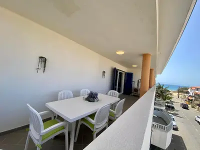 a dining room with a white table and chairs and the ocean at Leme Bedje Two bedroom - By Bobbywashere in Santa Maria
