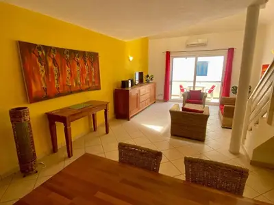 a living room with yellow walls and a table and chairs at Leme Bedje Two bedroom - By Bobbywashere in Santa Maria