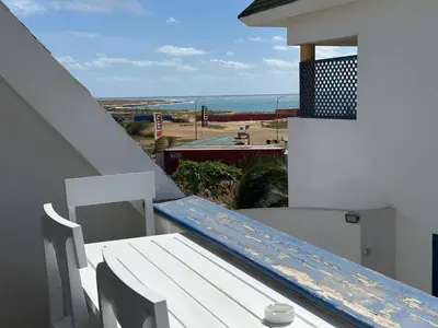a white bench on a balcony with a view of the ocean at Leme Bedje Two bedroom - By Bobbywashere in Santa Maria