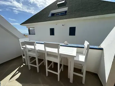 a white table and chairs on a balcony at Leme Bedje Two bedroom - By Bobbywashere in Santa Maria
