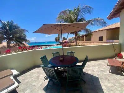 a table and chairs with an umbrella and the beach at Porto Antigo 1 - Three bedroom, pool & wifi in Santa Maria