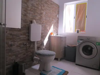 a bathroom with a toilet and a washing machine at Casa de Nômades Digitais in Mindelo