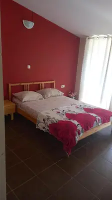 a bedroom with a bed with a red wall at SAM House in Mindelo