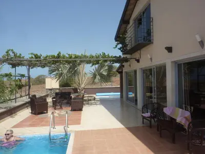 a woman in a swimming pool next to a house at Villa Halcyon cabo verde close to the beach in Cidade Velha