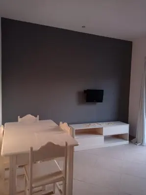a living room with a table and a tv on a wall at Apartamento Avenida in Sal Rei