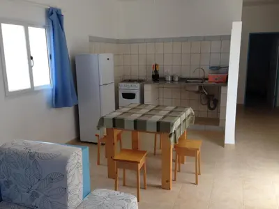a kitchen with a table with chairs and a refrigerator at Maio Relax in Vila do Maio