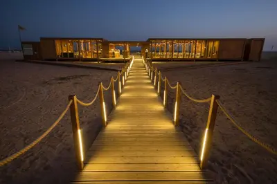 a wooden boardwalk leading to a building on the beach at Oasis Salinas Sea in Santa Maria