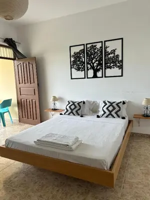 a bedroom with a bed with three pictures on the wall at Tarrafal Ecodécor Rooms in Tarrafal