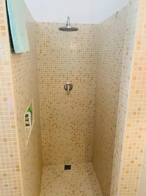 a bathroom with a shower with yellow tiled walls at Porto Antigo 2 Beach Club in Santa Maria