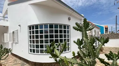 a white house with a large window at Djon’s place in Baia das Gatas