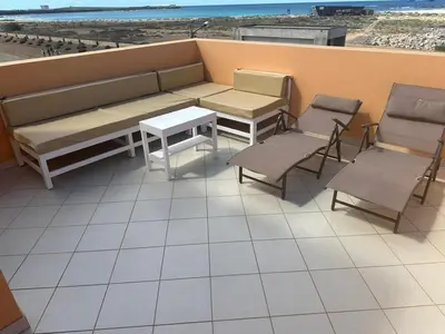 a bench and chairs on a balcony with the beach at Large Townhouse close to Beach in Sal Rei