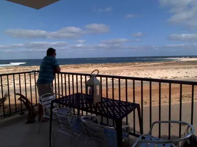 a man standing on a balcony looking at the beach at Vista Oceano - Boa Vista Island in Sal Rei