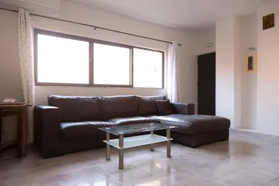 a living room with a leather couch and a table at 3 bdr cozy apt in Condominio Mi, Palmarejo Grande in Praia
