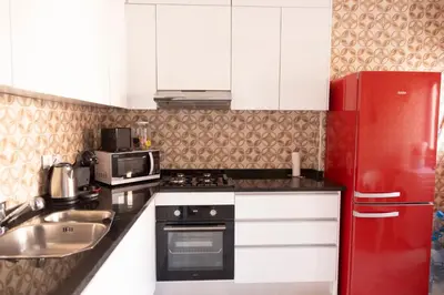 a kitchen with white cabinets and a red refrigerator at 3 bdr cozy apt in Condominio Mi, Palmarejo Grande in Praia