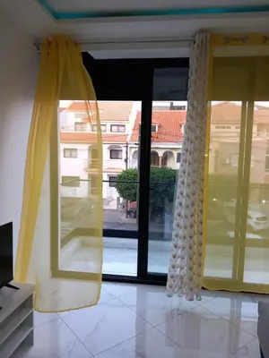 a room with a large window with yellow curtains at Edifício 2PALMA in Praia