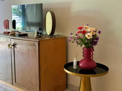 a vase with flowers on a table next to a mirror at Wind Holiday Apartments - By Bobbywashere in Santa Maria