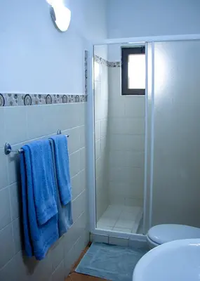 a bathroom with a shower with blue towels and a toilet at Porto Antigo 2 - Apt 54 in Santa Maria