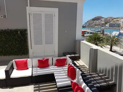 a white couch with red pillows on a balcony at Casa Café Mindelo in Mindelo