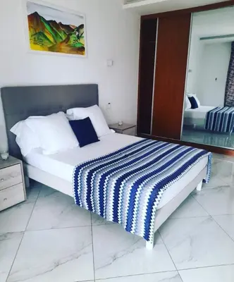 a bedroom with a bed with a blue and white striped blanket at Residencial Santo Amaro in Tarrafal