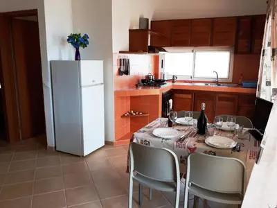 a kitchen with a table with chairs and a refrigerator at Casa Bahia 7 in Santa Maria