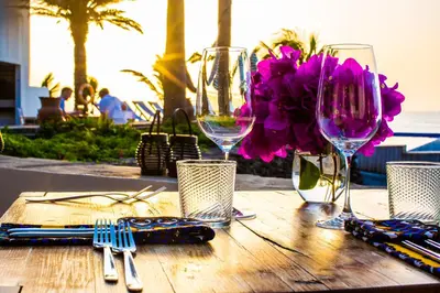 a wooden table with wine glasses and purple flowers on it at King Fisher Village Eco-Boutique Hotel in Tarrafal