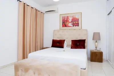 a bedroom with a white bed with red pillows at Nhu Sao Francisco - PALMAREJO T3 in Praia