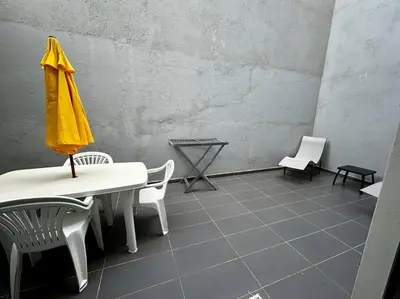 a room with a table and chairs and a yellow umbrella at Modern Apartment in Praia Baixo - 1 min Walking to Beach in Praia Baixo