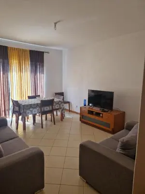 a living room with a couch and a tv and a table at Condomínio palma azul II in Praia