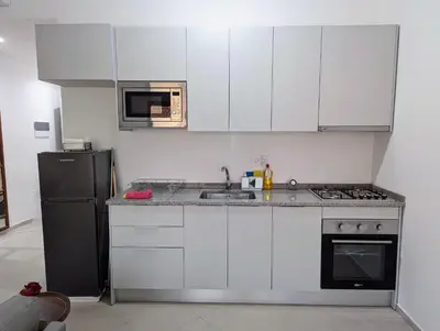 a kitchen with white cabinets and a black refrigerator at Tarrafal Bay - 1Bdr Apt - Sea view -1 in Tarrafal