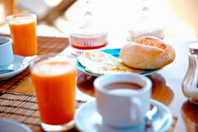 a table with a plate of breakfast food and a cup of coffee at Casa Strela B&B Tarrafal in Tarrafal