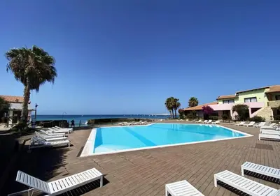 a swimming pool with lounge chairs and the ocean at Beautiful loft in Porto Antigo 1 in Santa Maria