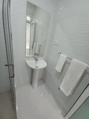 a white bathroom with a sink and a shower at Apto T0 na Capital in Praia