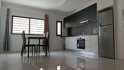 a kitchen with a table and chairs and a refrigerator at T2 da Marília fonte francês in Mindelo