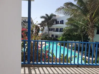 a balcony with a blue railing and a swimming pool at Holiday Properties Leme Bedje in Santa Maria