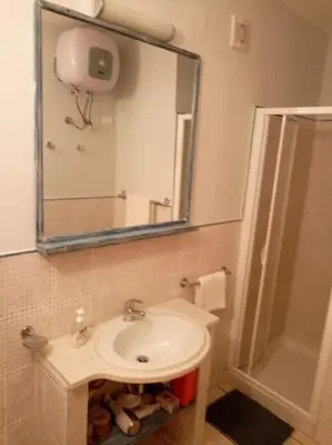 a bathroom with a sink and a shower and a mirror at Apartamento Djadsal Moradias L01 próximo à praia in Santa Maria