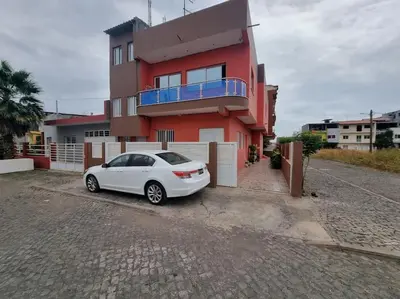 a white car parked in front of a red house at Jbct & SOLANGE APART in Praia