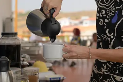 a woman is pouring coffee into a cup at Encosta Azul in Cidade Velha