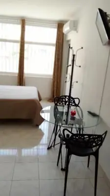 a living room with a glass table and a bed at Estúdio Vieira in Praia