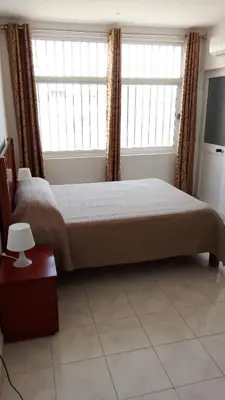 a bedroom with a large bed and two windows at Estúdio Vieira in Praia
