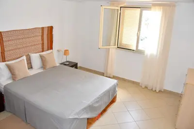 a bedroom with a white bed and a window at Kyaala Djadsal Moradias pool&sea in Santa Maria