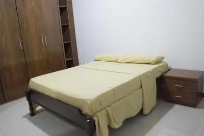 a bedroom with a bed and a wooden cabinet at T1 conforto in Praia