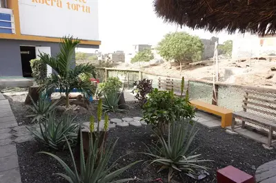 a garden with plants and a bench in front of a building at Residencial Ribeira Torta in Porto Novo