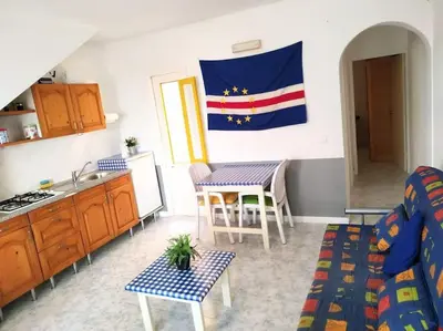 a living room with a kitchen and a flag on the wall at Feeling Cabo Verde in Beirona