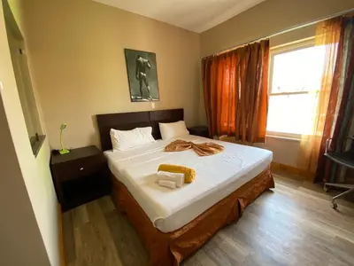 a bedroom with a bed with white sheets and a window at Spencer Residencial QUARTOS in Praia